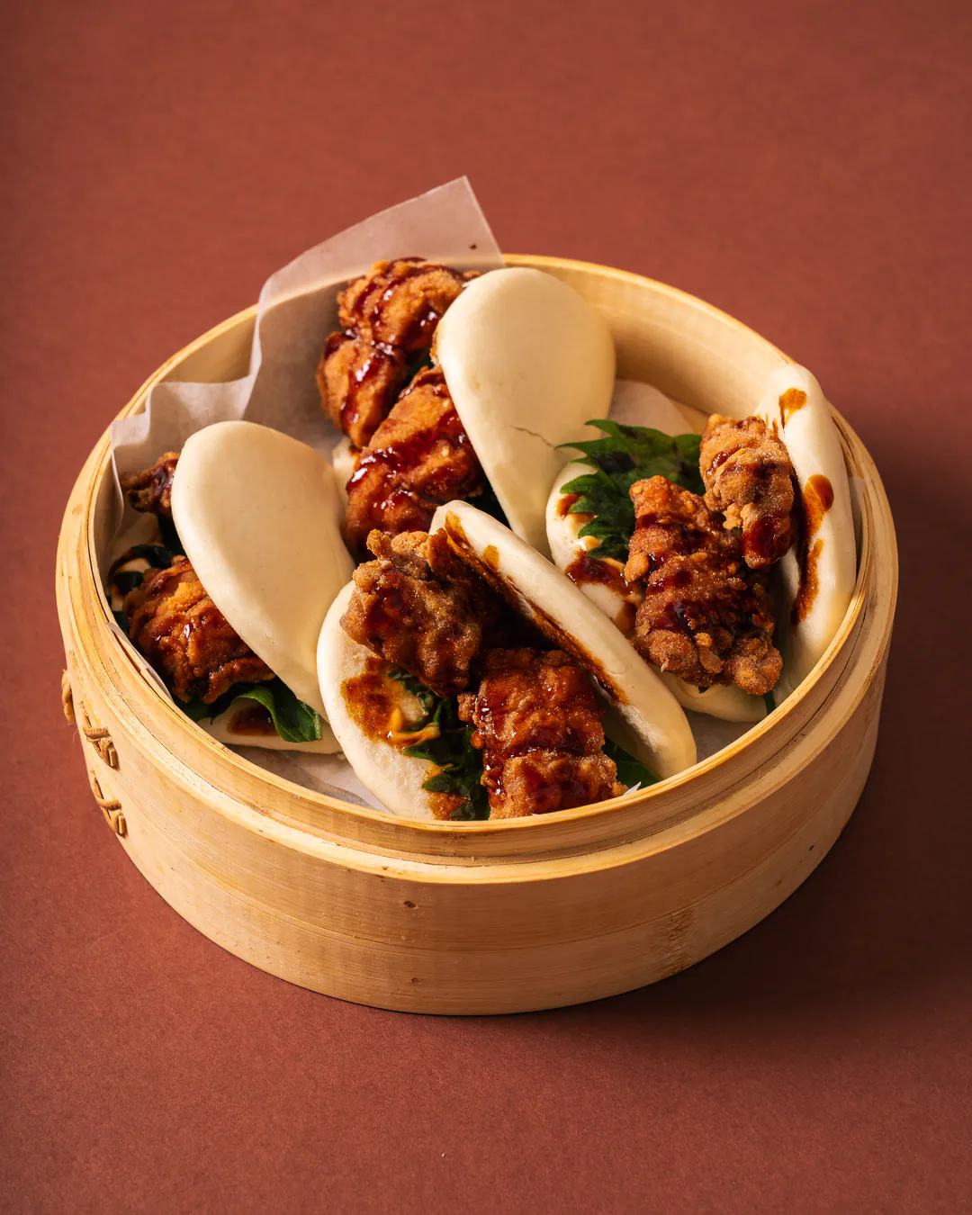Bao al vapore con karaage di branzino nel cestino di bambù
