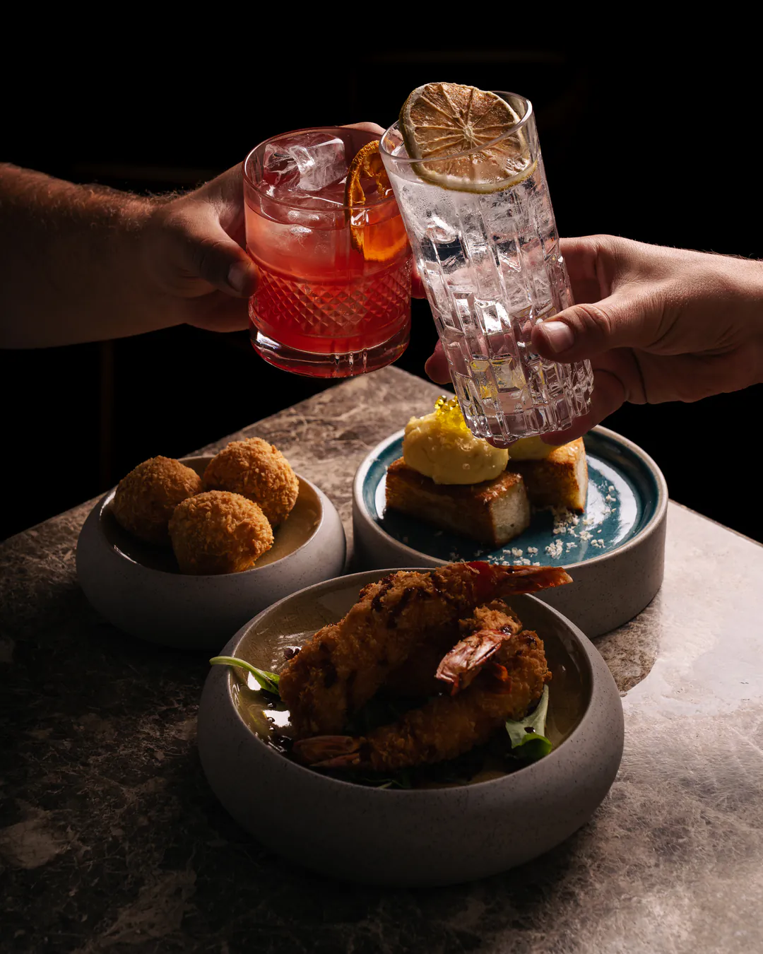 Un brindisi con due cocktail sopra tre antipasti