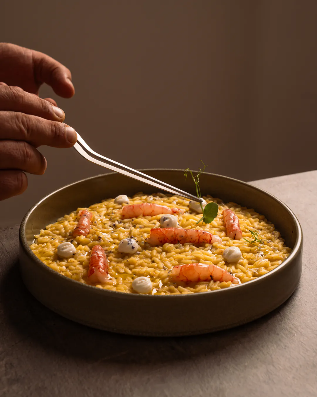 Le pinzette sistemano un risotto nel piatto